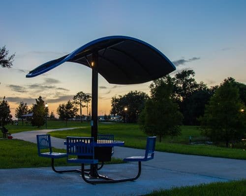 Shaded picnic table on a park path at dusk
